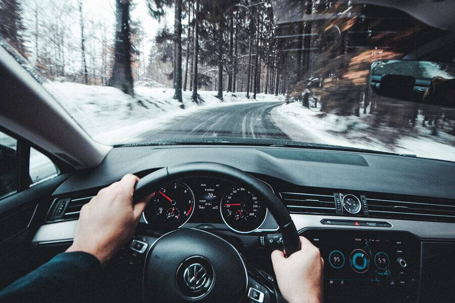 Interior view of a car and driver on the road.